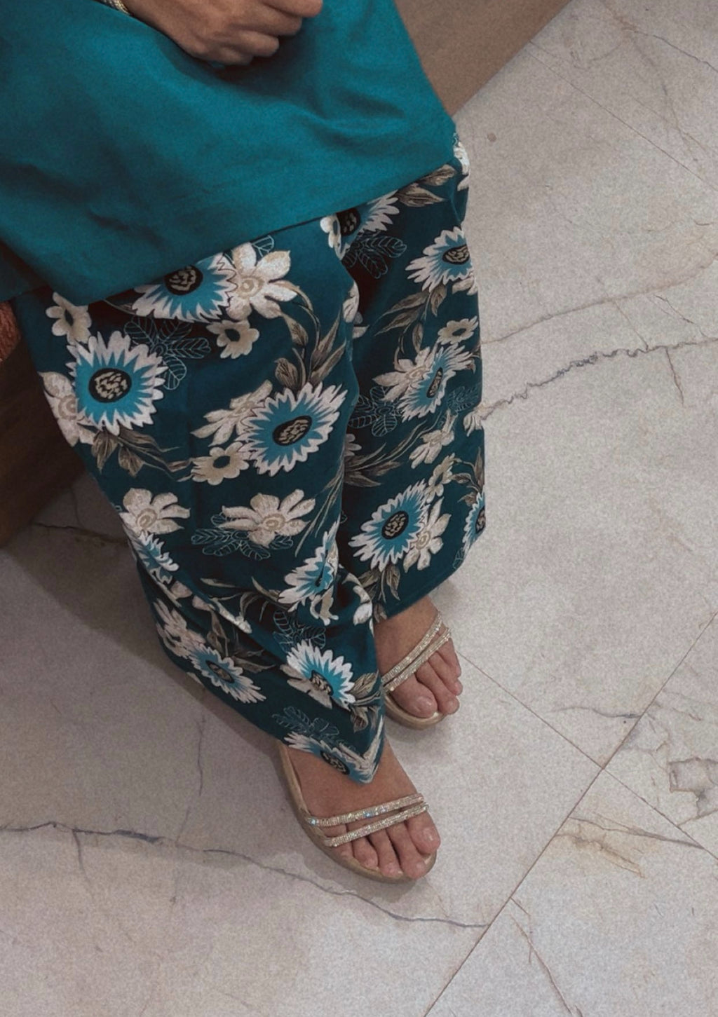 Person wearing teal floral pants on a marble floor